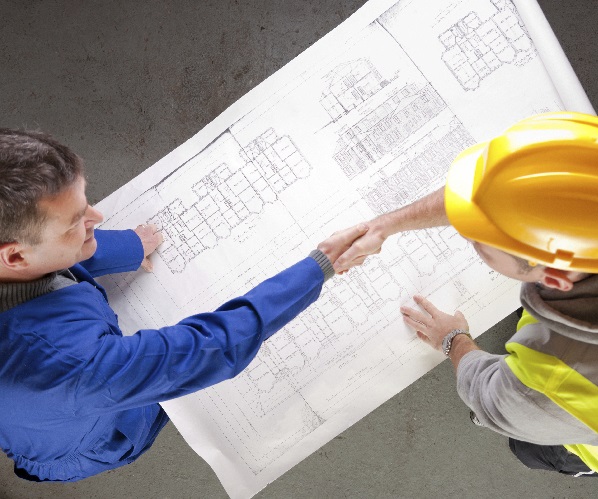 Builders shake hands over construction blueprint